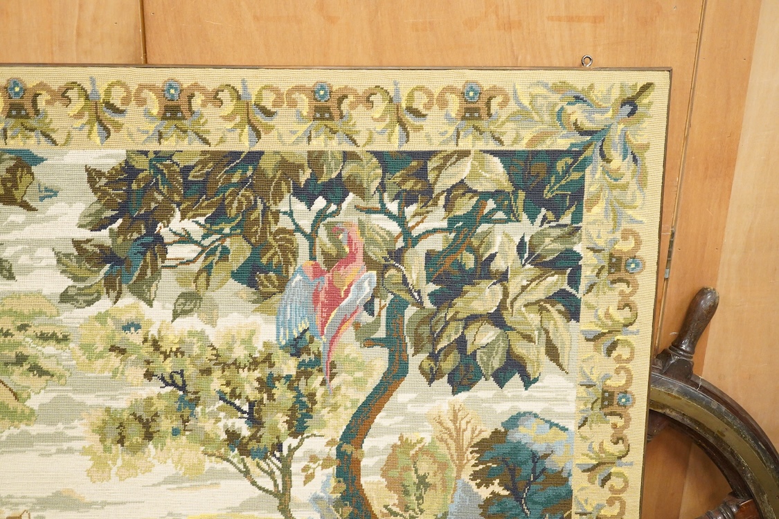 A large framed gross point wool work panel, designed in a verdure foliate palette as a classical French landscape. 161cm wide x 132 cm high.
